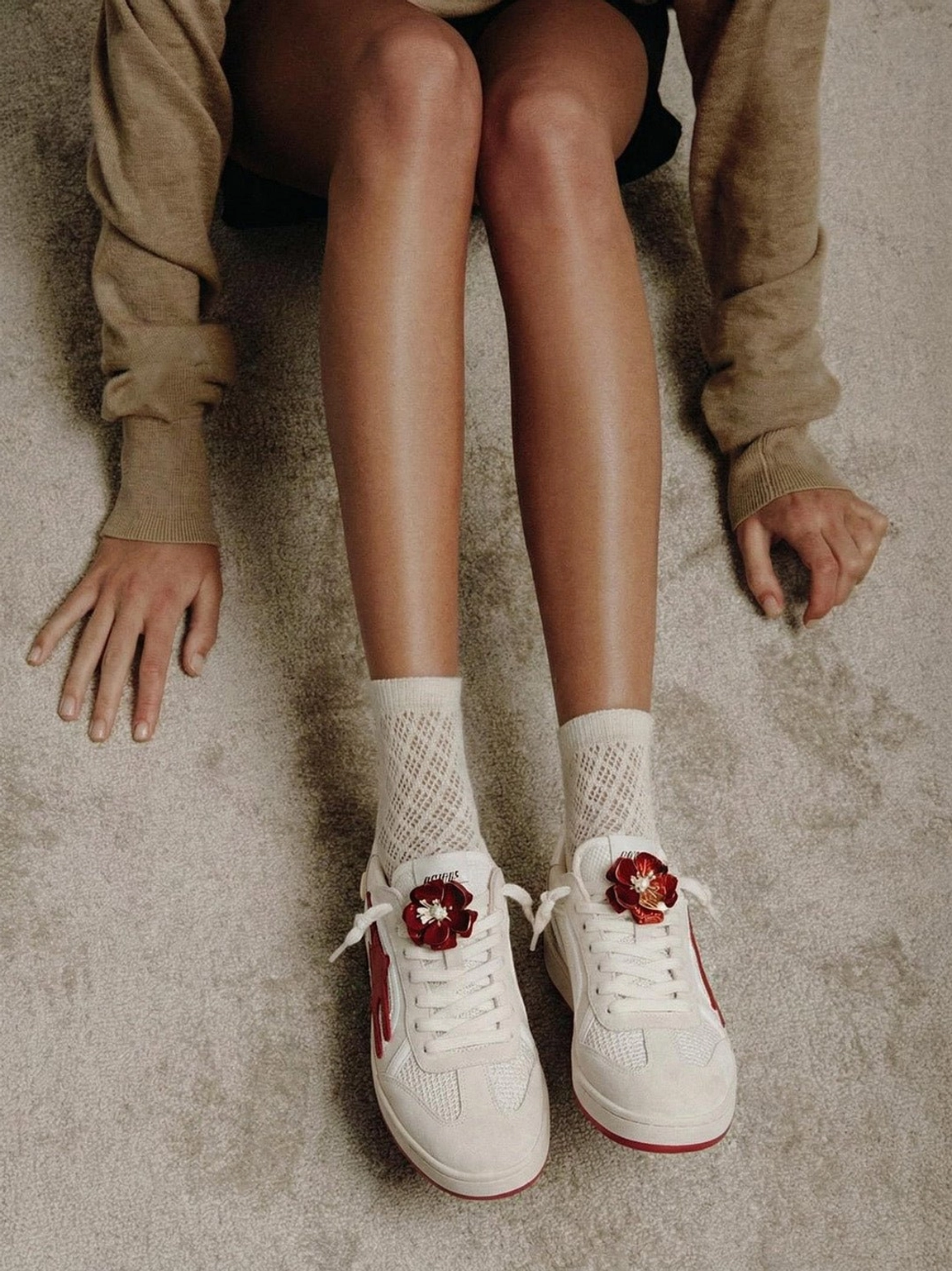 Top-down view of beige and red retro training sneakers worn with a beige knit outfit and coordinating crew socks