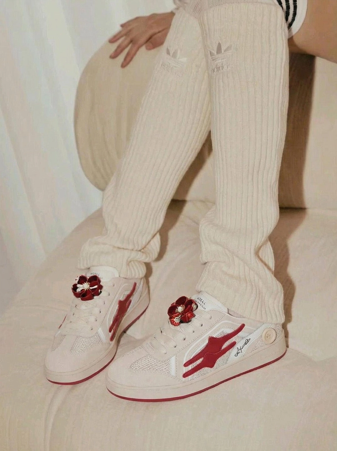 Unisex beige and red retro sneakers worn with cream ribbed knit pants and over-the-knee socks in a casual streetwear styling view