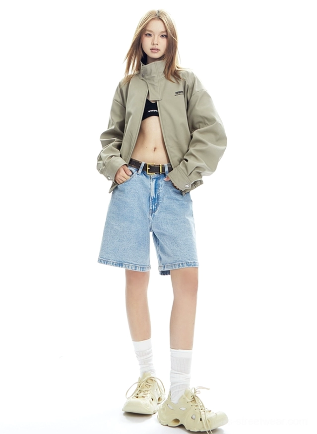 Front three-quarter outfit view featuring a relaxed beige cropped bomber jacket over a black crop top with denim and casual sneakers