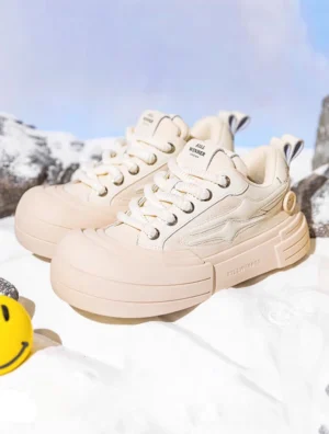 Pair of beige smile platform sneakers shown on snowy rocks with yellow smiley decorations, star side accents, and coordinated streetwear styling