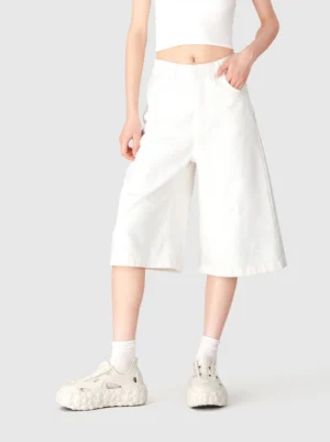 Model wearing beige star platform sandals with white crew socks, cropped tank top, and wide-leg culottes in a monochrome streetwear outfit
