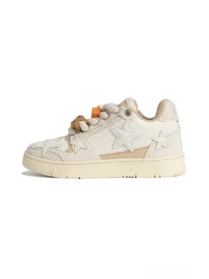 Beige star low-top streetwear sneaker with dimensional lace panels, cowhide star applique, chunky rope laces, decorative lace charms, and distressed rubber sole shown in side view