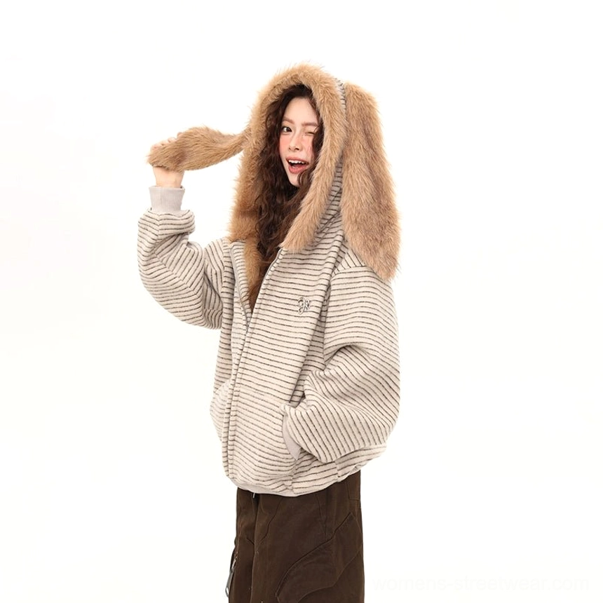 Close-up view of a playful beige striped bunny-ear hoodie with warm brown faux-fur trim and relaxed oversized streetwear silhouette