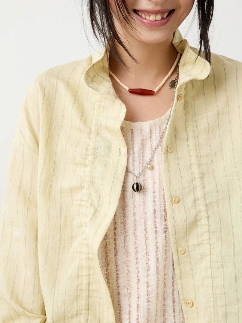 Close-up view of the beige textured Mandarin collar shirt showing the vertical stripe texture, round buttons, and layered camisole neckline