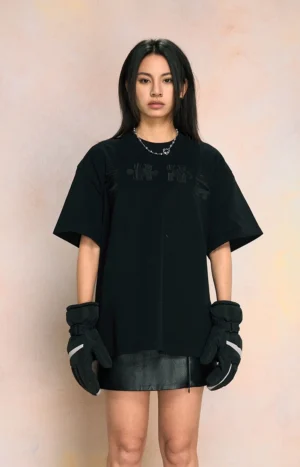 Black 3D puzzle embroidered oversized streetwear tee with subtle tonal chest detail worn with a leather mini skirt