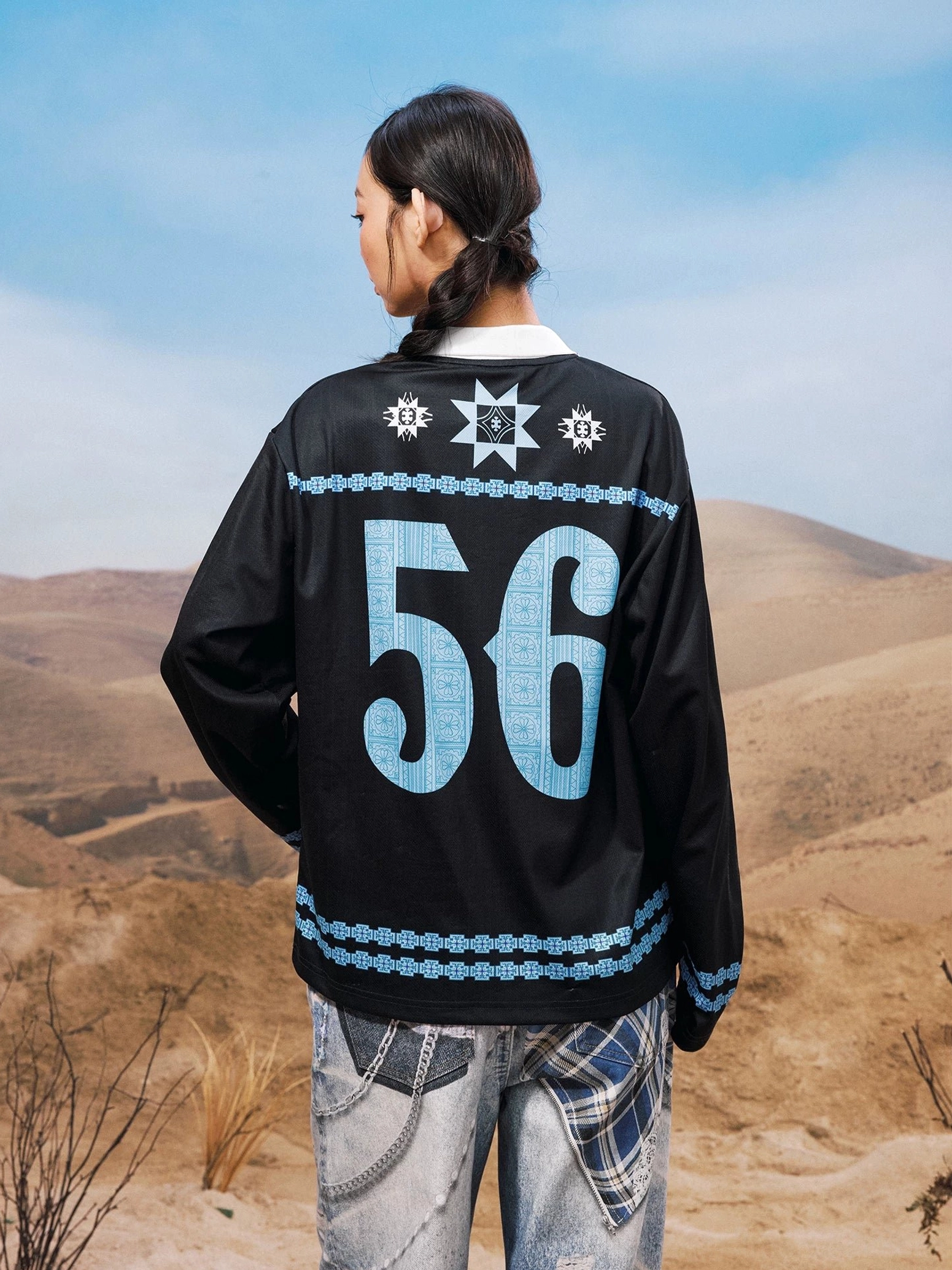 Back view of black oversized graphic football jersey inspired streetwear shirt featuring a large light blue 56 graphic and decorative blue trim