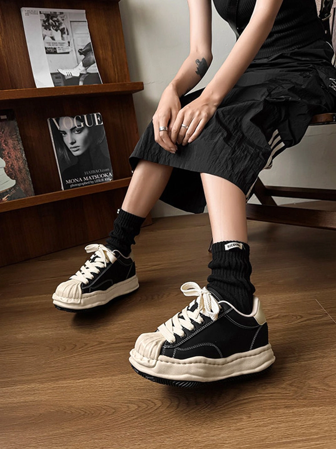 Black 7cm distressed platform sneakers styled with a black streetwear dress and stacked socks in a studio setting