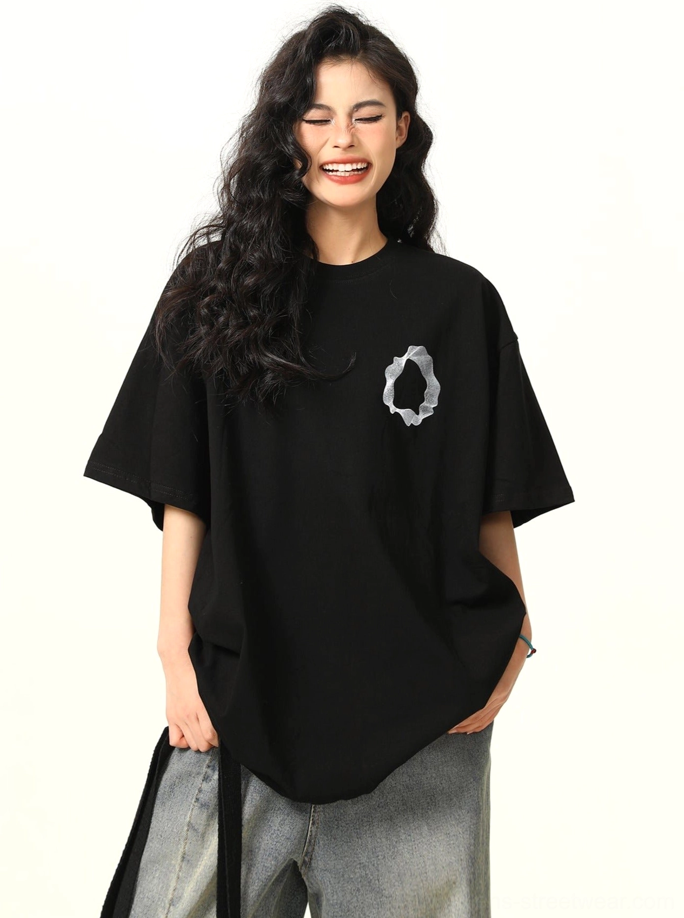Front view of relaxed drop shoulder black abstract ring graphic tee with curved hem and loose gray denim styling