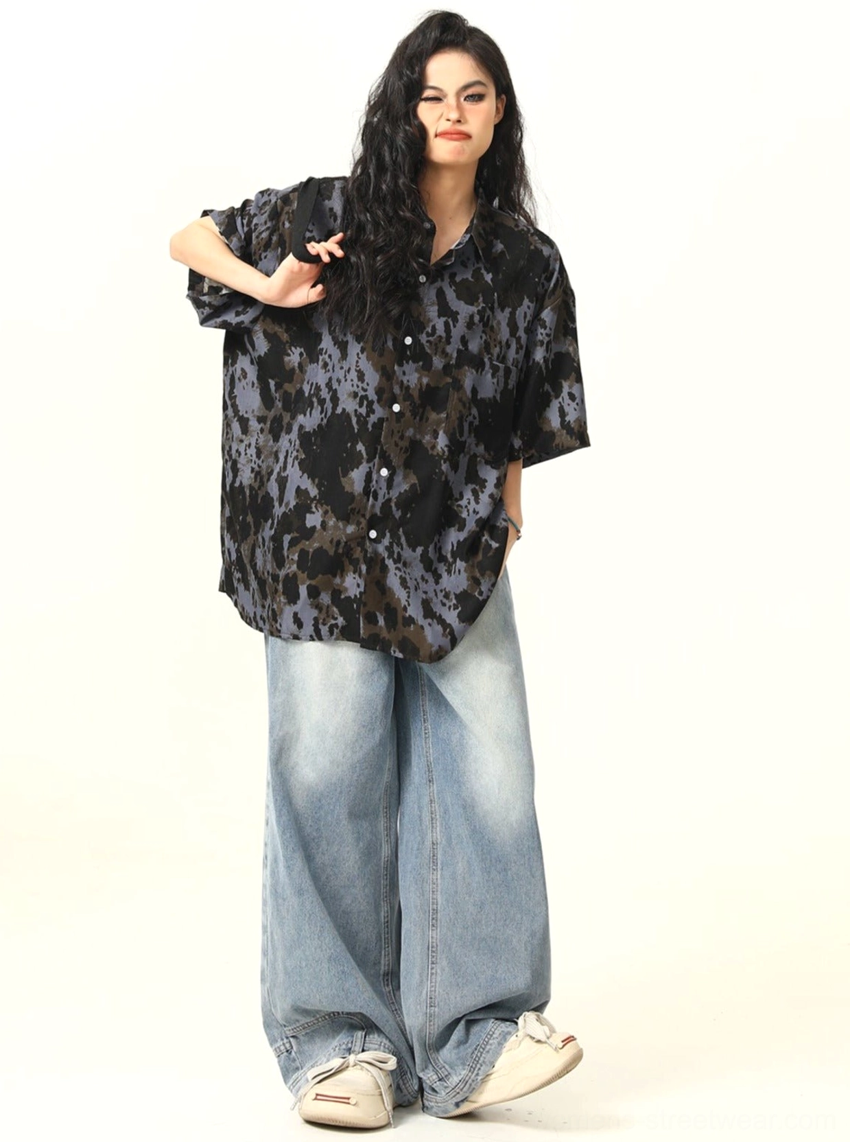 Front casual styling view of black abstract tie-dye oversized button-up shirt with denim jeans and white sneakers