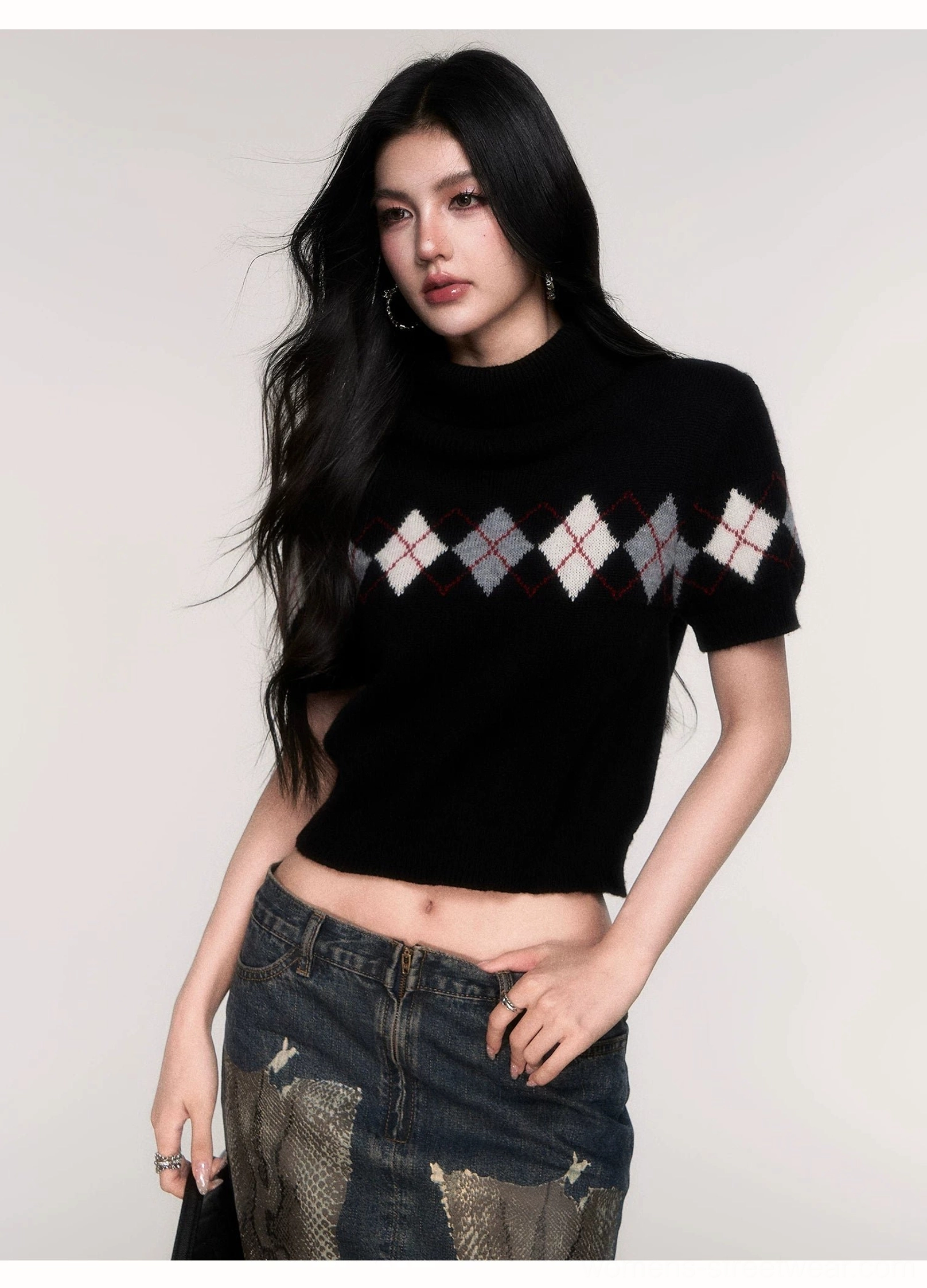 Front view of a black cropped argyle knit sweater with soft turtleneck collar, short puff sleeves, fitted waist-level silhouette, and classic contrast diamond pattern