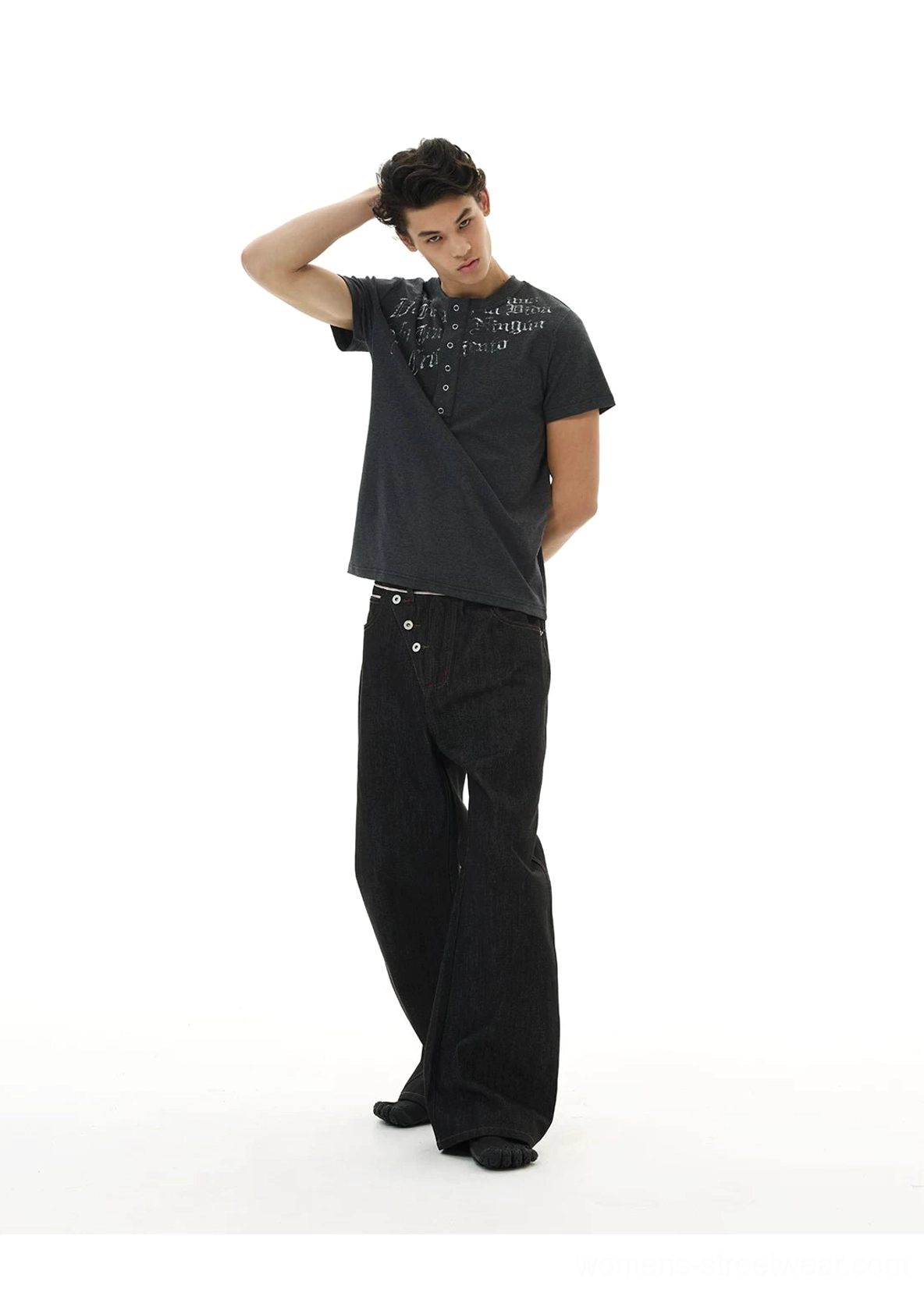 Side three-quarter view of black asymmetric button waist jeans with relaxed wide-leg streetwear fit