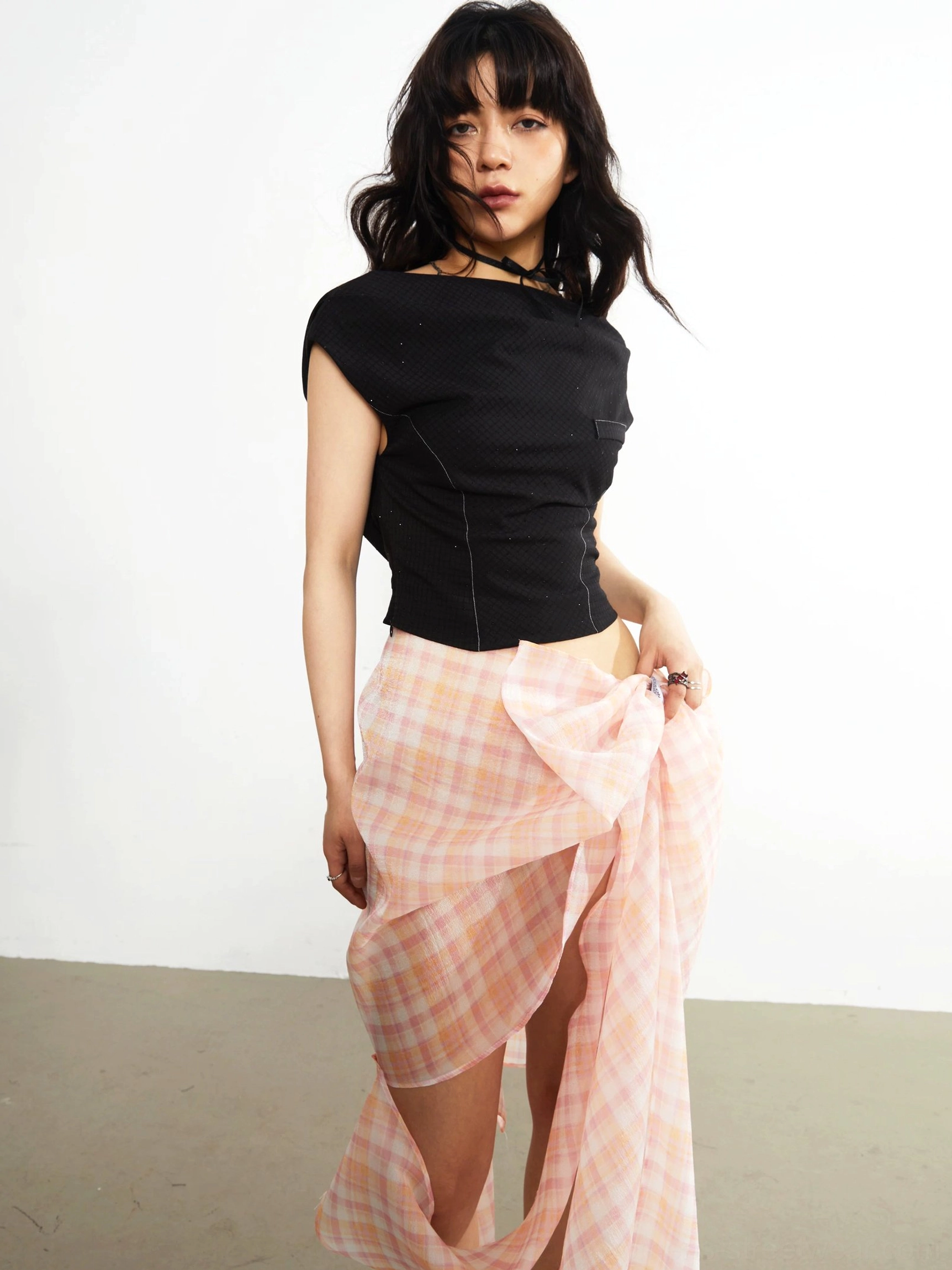 Black asymmetric cropped knit top three-quarter front view with capped sleeves fitted waist and exposed midriff