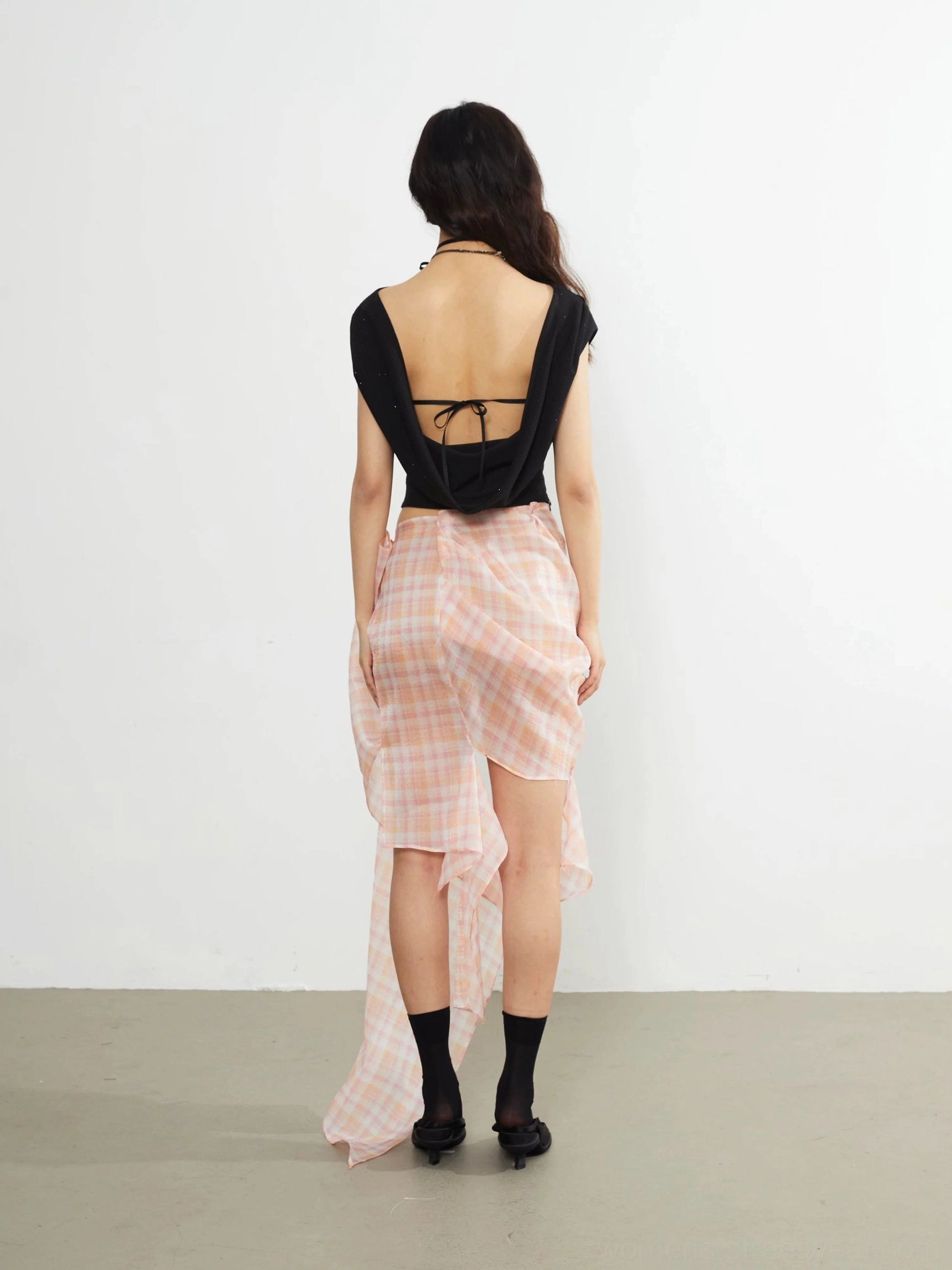 Black asymmetric cropped knit top back view with open back tie closure and contrast decorative stitching