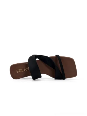 Top view of black asymmetric cross strap slide sandal with square toe and brown footbed