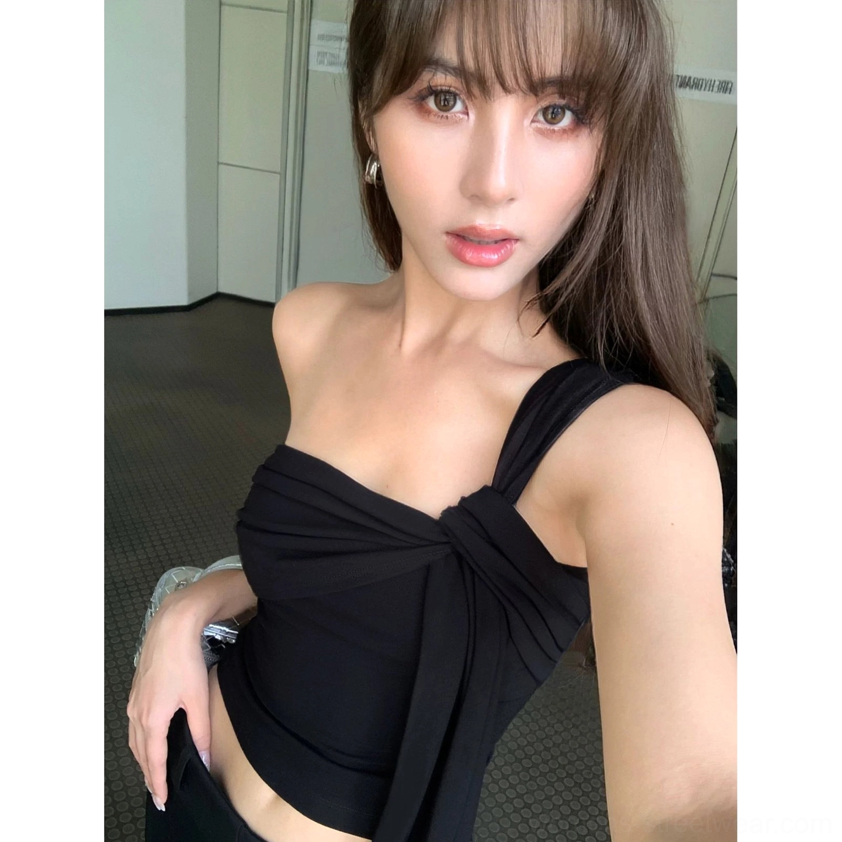 Black asymmetric draped one-shoulder crop top with sleek minimalist styling and statement shoulder tie