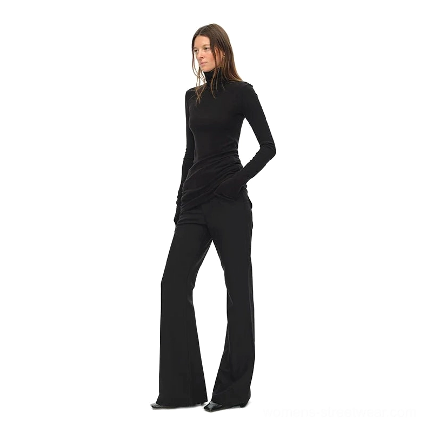 Side view of black fitted turtleneck knit top with long sleeves styled with black flared trousers