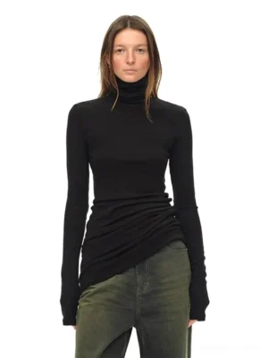 Black fitted turtleneck knit top with asymmetric draped hem styled with vintage green wide-leg jeans