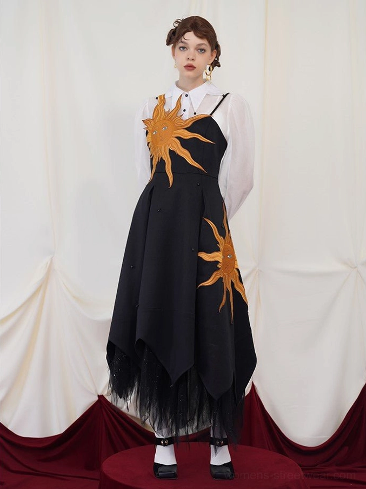 Front view of a black asymmetric embroidered maxi dress with golden sun motifs, sheer blouse, white socks, and Mary Jane shoes