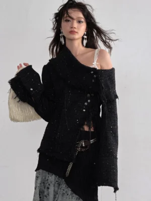 Black asymmetric frayed tweed off shoulder jacket worn by model in a minimalist studio front three quarter view