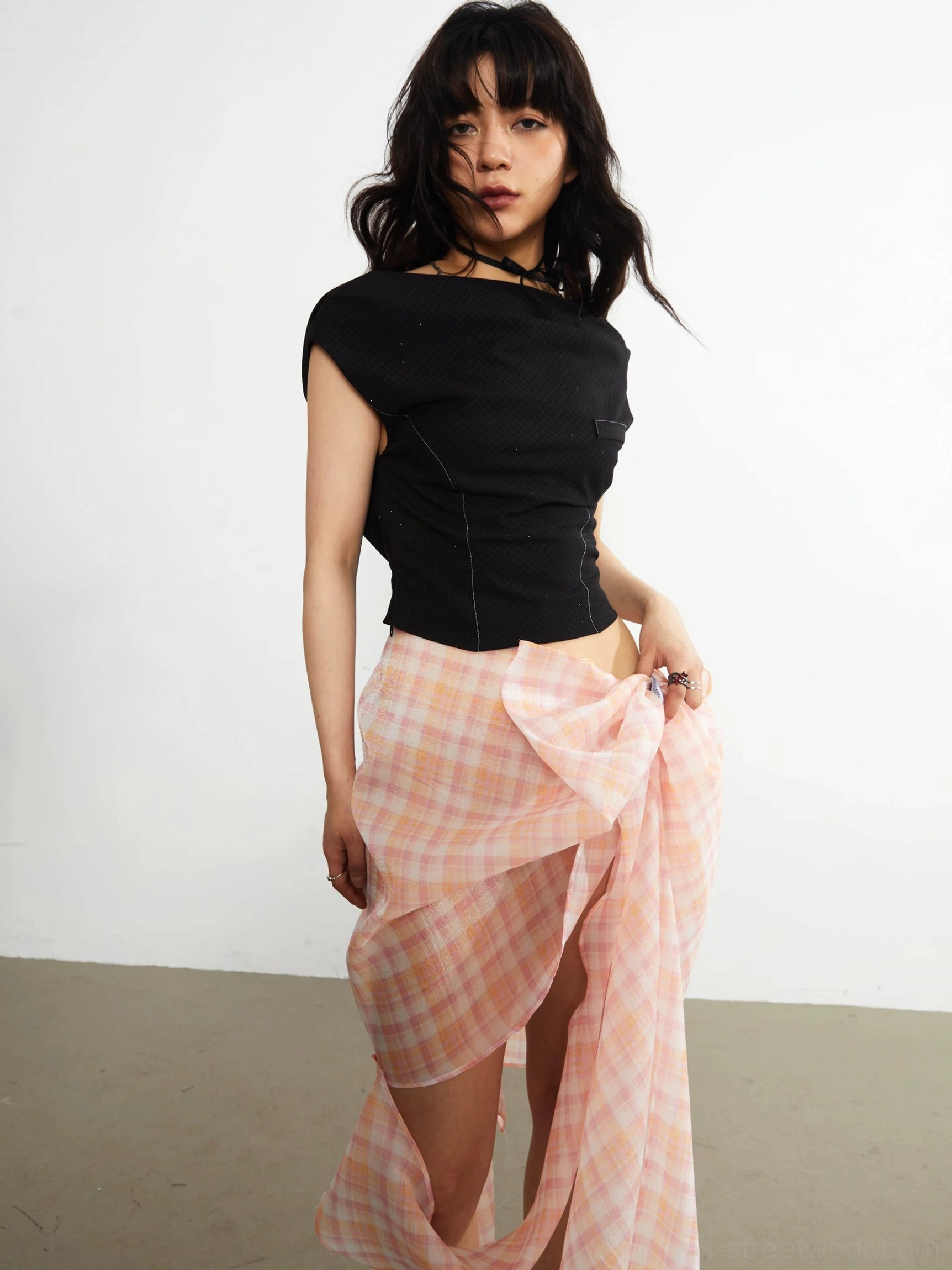 Black asymmetric knit crop top three-quarter front view with draped neckline capped sleeves and slim cropped silhouette
