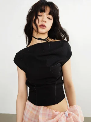 Black asymmetric knit crop top front close-up with draped neckline contrast stitching and pink plaid streetwear skirt