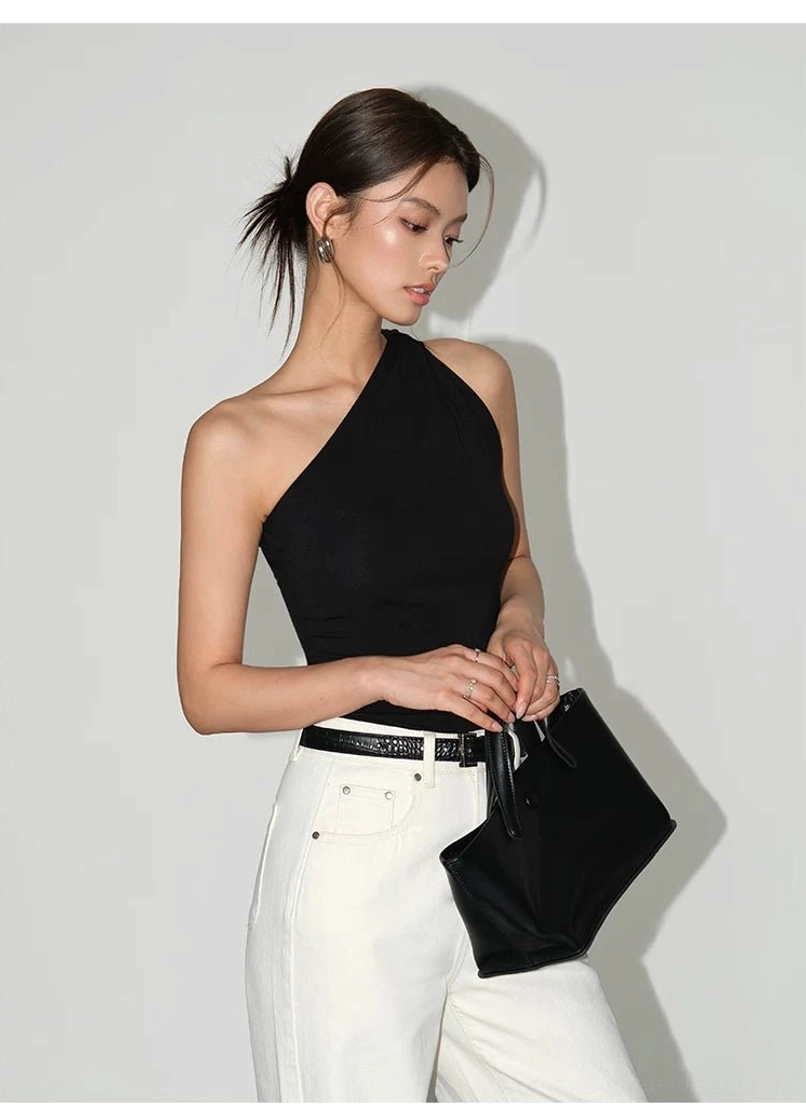Black women's one-shoulder knit tank top with asymmetric neckline styled with white belted trousers and a black handbag
