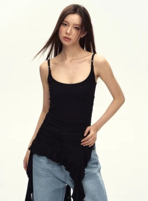 Black asymmetric ruched cami top with adjustable spaghetti straps and flowing ruffled hem styled with loose light blue jeans