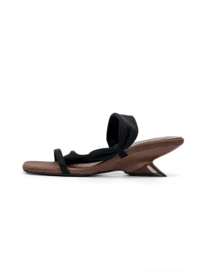 Black asymmetric strap slide sandal with square open toe and sculptural low wedge heel shown in left side profile