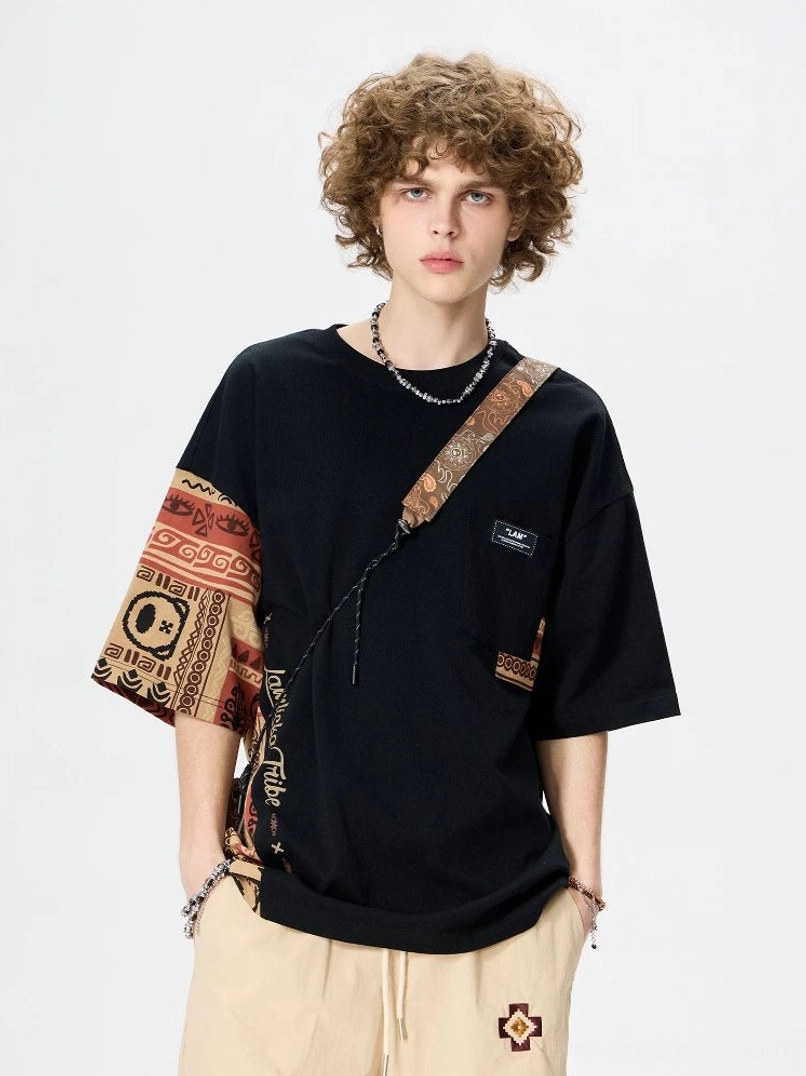 Black asymmetric tribal panel oversized cotton T-shirt front view with contrast sleeve, side insert, and chest patch detail