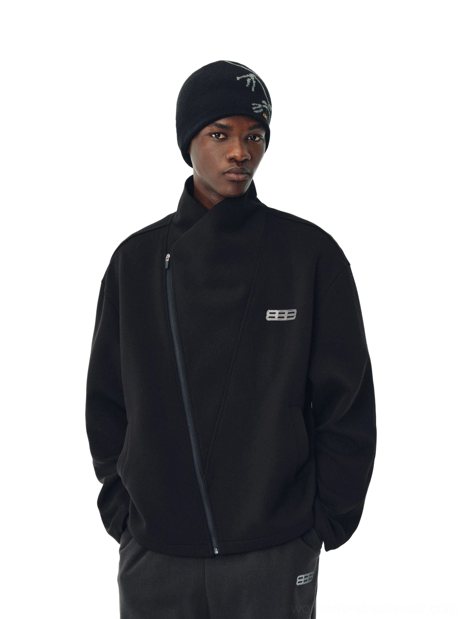 Black asymmetric zip high-neck streetwear jacket on a male model wearing a knit beanie with relaxed dropped shoulders