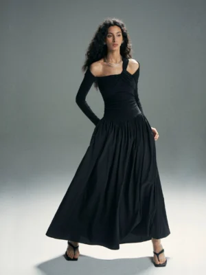 Black asymmetrical cold-shoulder maxi dress shown from the front three-quarter angle with a fitted bodice, long sleeve, and gathered floor-length skirt