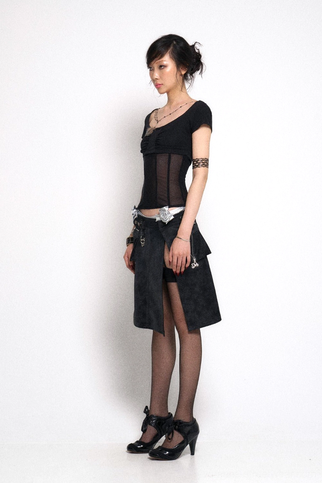 Side view of black asymmetrical gothic cargo mini skirt with hardware details side slit and mini pocket