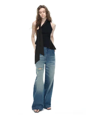Black asymmetrical halter top with adjustable long side tie sash styled with ripped wide-leg blue jeans front full body view