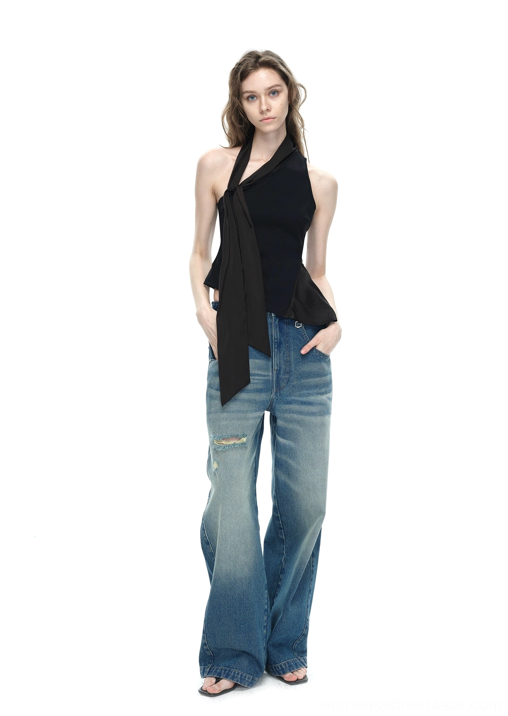 Black asymmetrical halter neck top with long side tie sash paired with ripped wide-leg jeans full body studio view