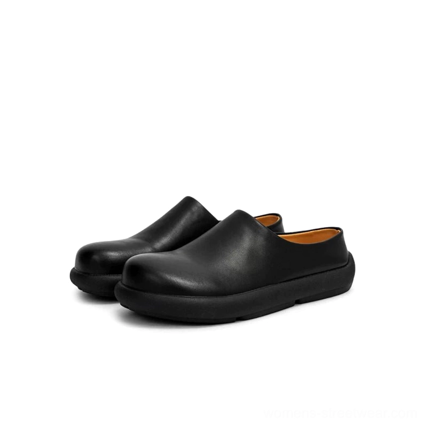 Black leather-inspired backless mule clogs displayed from the front, featuring a smooth matte finish, rounded closed toe, and durable chunky rubber sole