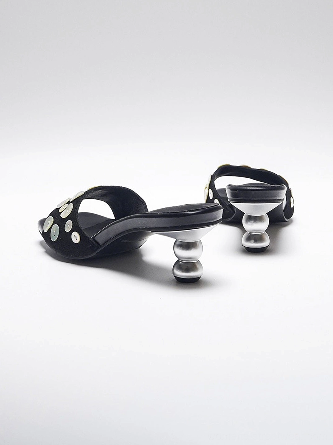 Black backless high heel slide sandals with silver disc strap accents and modern square open toe