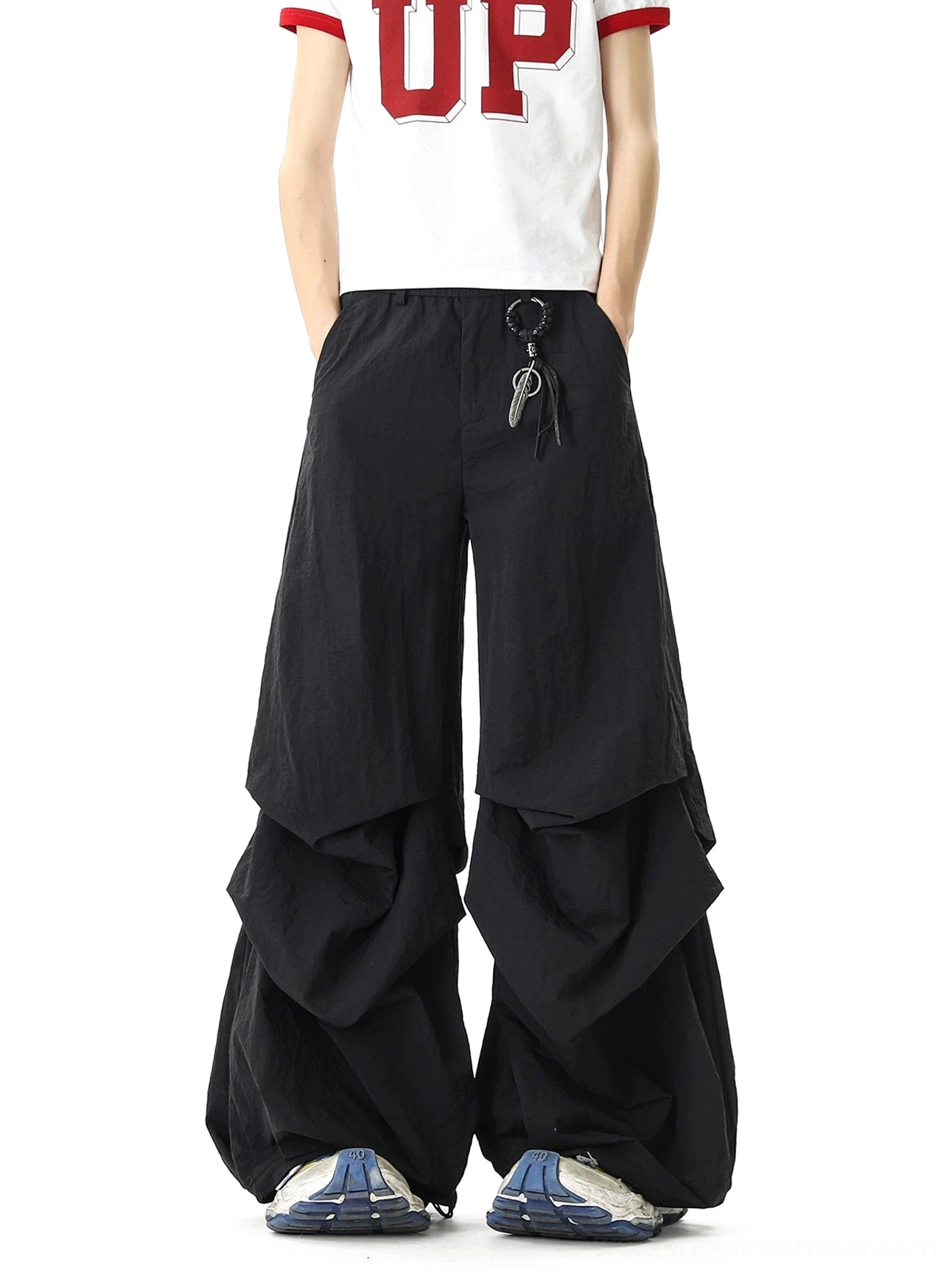 Straight-on full-body view of black balloon parachute streetwear pants with ultra-loose layered legs, elastic waist, side pockets, and utility-inspired key ring decoration
