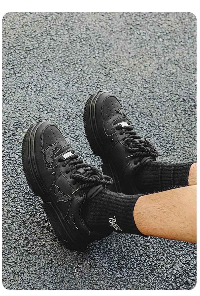 Close overhead view of black bat themed platform sneakers showing thick split sole, rope laces, and wing side decorations