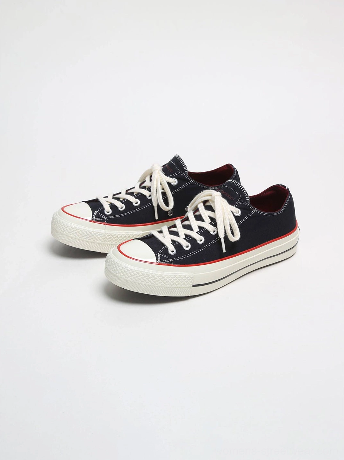 Three-quarter studio view of black bat print canvas platform sneakers with burgundy lining, red toe trim, and off-white vulcanized midsoles