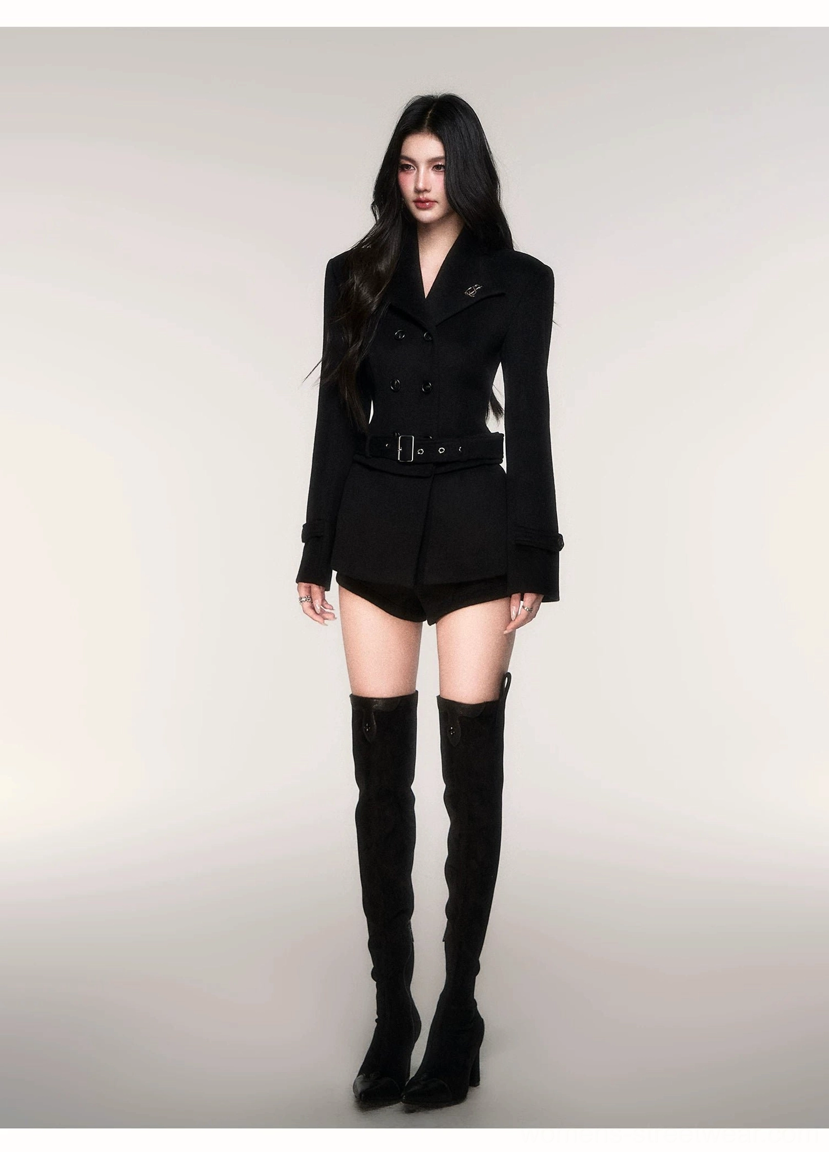 Black belted double breasted peacoat styled with matching shorts in a minimalist streetwear studio look