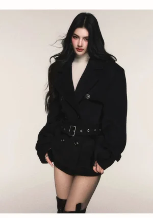 Black belted double-breasted wool blend peacoat styled with cream turtleneck, mini shorts and over-the-knee boots front view