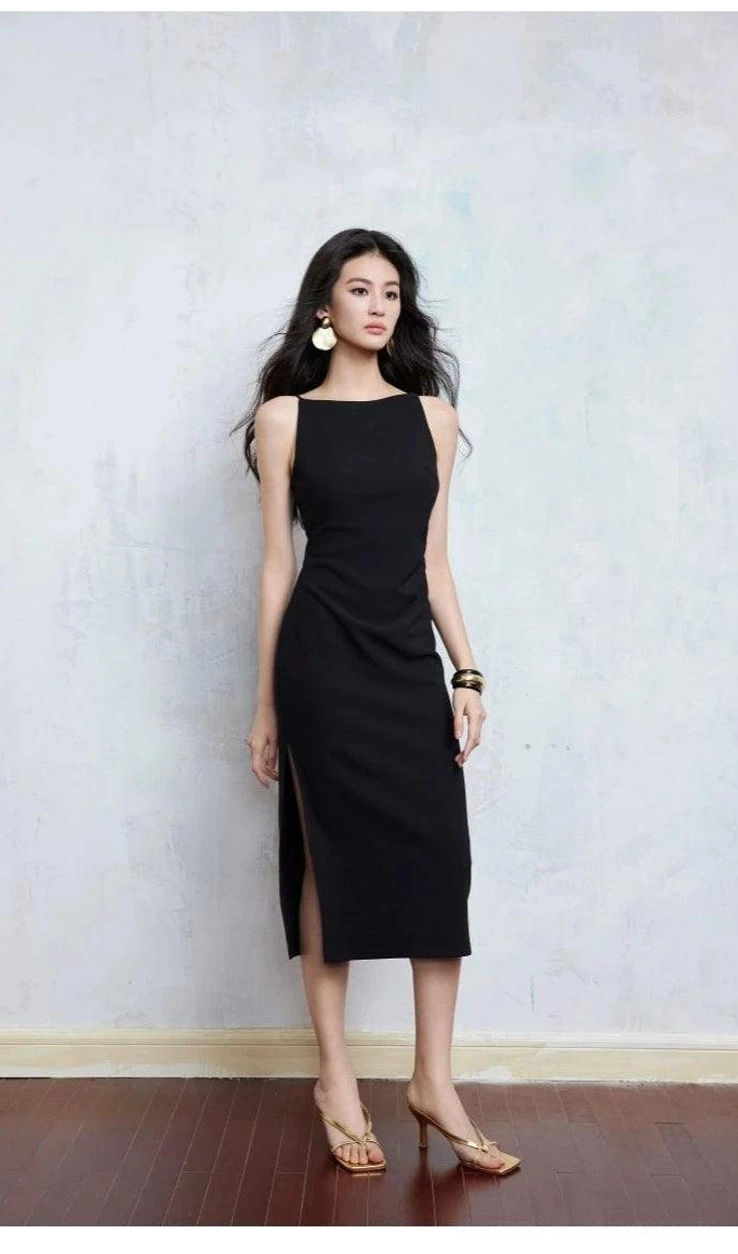 Black sleeveless bodycon midi dress with side slit, boat neckline, tan strappy heels, and modern streetwear styling