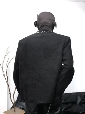 Back view of a black bouclé wool-blend streetwear jacket featuring pearl embellishments at the neckline, padded shoulders, structured silhouette, textured fabric, and raw frayed hem