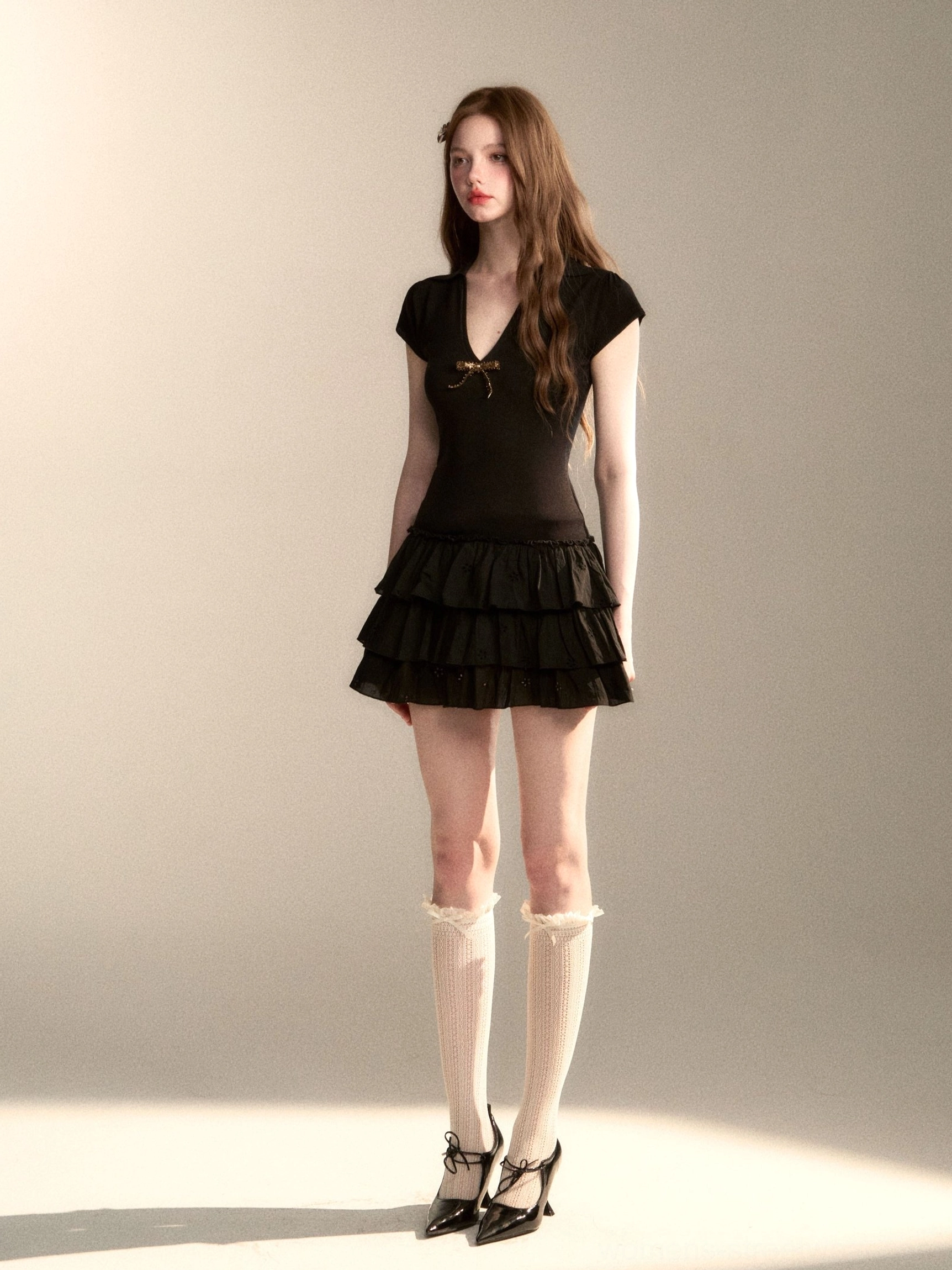 Black bow detail mini dress with V-neck cap sleeves and voluminous multi-layer ruffle skirt in studio