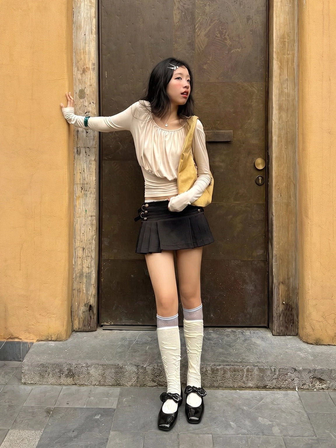 Full-body outfit featuring black bow square-toe Mary Jane flats, beige long-sleeve top, and pleated mini skirt