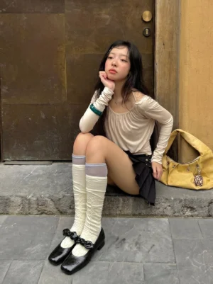 Model wearing black bow square-toe Mary Jane flats with pleated mini skirt, knee-high socks, and retro Korean streetwear outfit