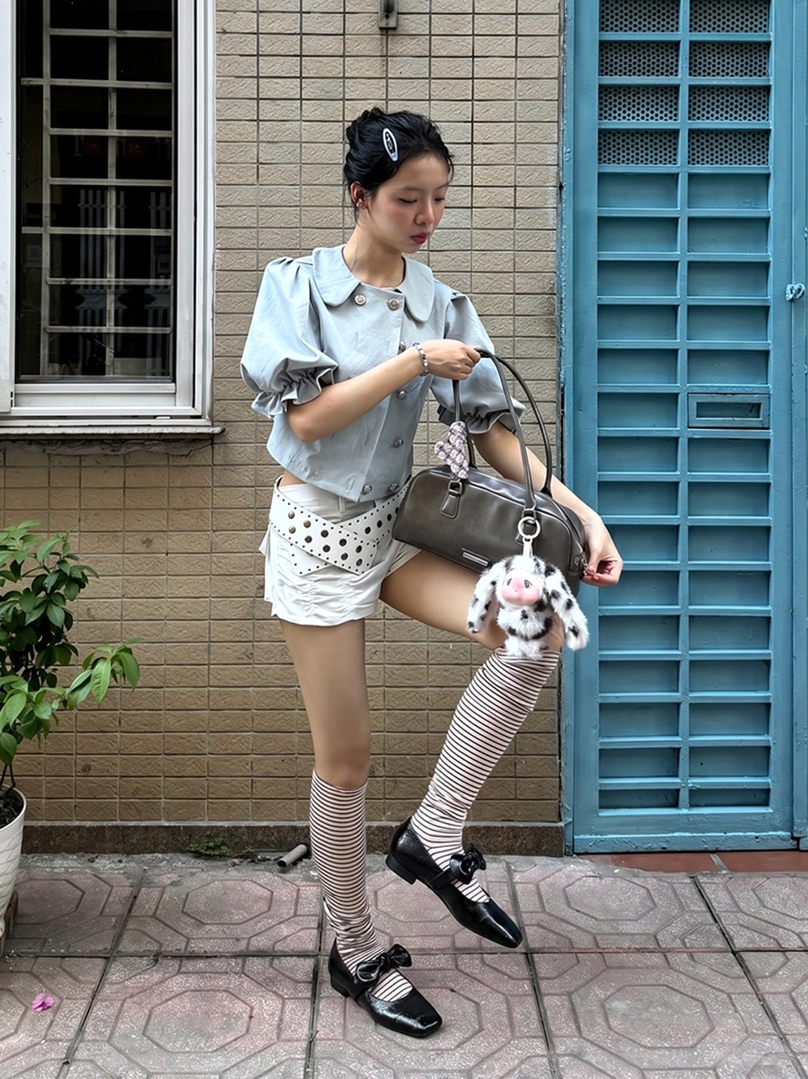 Black bow square-toe strap flats styled with striped socks, cropped blouse, and denim shorts for casual streetwear
