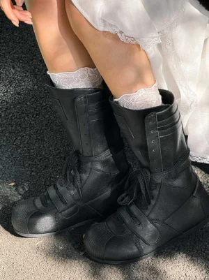 Model wearing black boxing-inspired platform boots with white lace-trimmed socks and a ruffled dress in an outdoor Y2K streetwear outfit