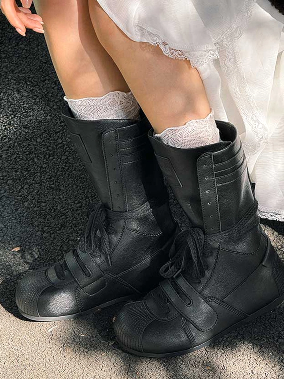 Model wearing black boxing-inspired platform boots with white lace-trimmed socks and a ruffled dress in an outdoor Y2K streetwear outfit