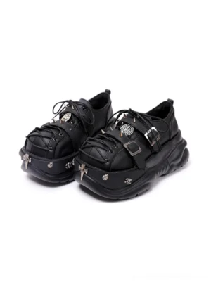 Black buckle cage chunky platform sneakers shown from the front three-quarter view with cross-inspired toe charms, layered straps, metal buckles, and oversized lug soles